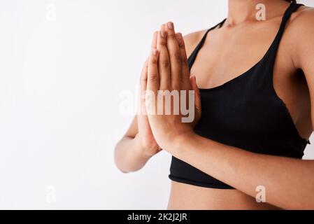 Frieden ist eine Yoga-Sitzung entfernt. Aufnahme einer nicht erkennbaren Frau, die mit ihren Händen vor weißem Hintergrund posiert. Stockfoto