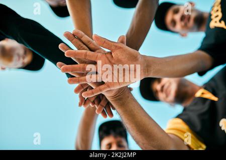 Jeder Spieler spielt eine große Rolle. Aufnahme eines Teams junger Baseballspieler, die sich während eines Spiels in einer Gruppe zusammenschließen. Stockfoto