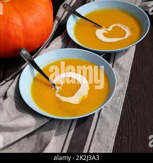 Frische Kürbis-Sahnesuppe zum Herbstessen auf rustikalem Tisch Stockfoto