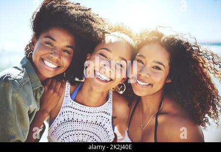 Waren am glücklichsten, wenn sie zusammen waren. Eine Aufnahme von drei Freunden, die sich an einem sonnigen Tag am Strand Vergnügen. Stockfoto