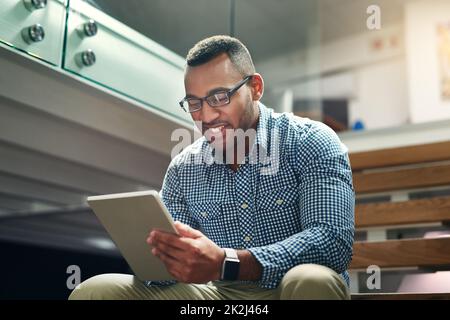 Einen anderen Arbeitsplatz finden. Eine kleine Aufnahme eines hübschen jungen Geschäftsmanns, der sein Tablet im Büro benutzt. Stockfoto