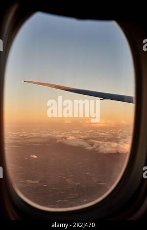 Stellen Sie sicher, dass Sie einen Fensterplatz bekommen. Zugeschnittene Aufnahme der Ansichten aus einem Flugzeugfenster. Stockfoto