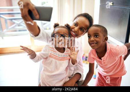 Glückliche Momente festhalten. Eine kurze Aufnahme einer liebevollen jungen Familie, die zu Hause Selfies macht. Stockfoto