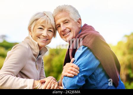 Wahre Liebe ist unendlich. Porträt eines glücklichen älteren Paares, das auf einer Parkbank sitzt. Stockfoto