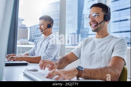 Gemeinsam können wir mehr erreichen. Aufnahme von zwei Geschäftskollegen, die an ihren Schreibtischen in ihrem Büro zusammenarbeiten. Stockfoto