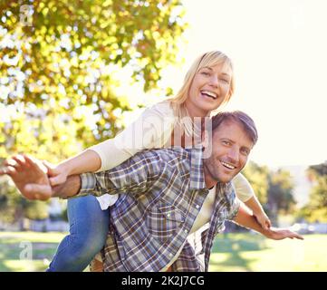 Liebe macht dich wieder wie Kinder. Aufnahme eines glücklichen Mannes, der seine Frau huckepack. Stockfoto