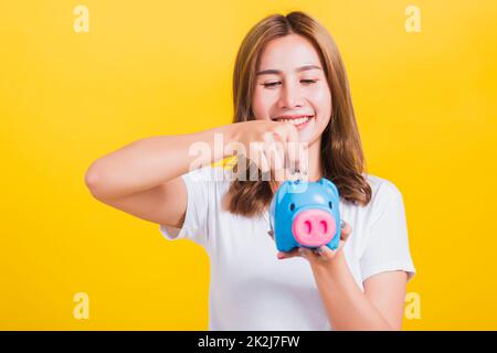 Lächelnde Frau hält Sparschwein mit viel Geld Stockfoto