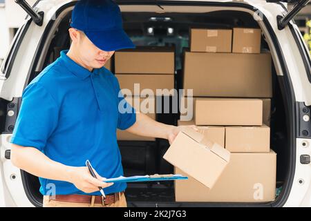 Der man-Kurier in Uniform hält Dokumente in der Zwischenablage, Checkliste Paketpostkartons Stockfoto