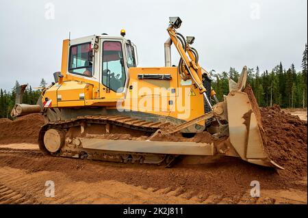 Ein gelber Traktor legt den Standort mit Sand ab Stockfoto