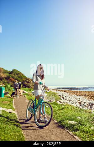 Was für ein schöner Tag für eine Radtour. Porträt einer attraktiven jungen Frau, die draußen mit dem Fahrrad unterwegs ist. Stockfoto