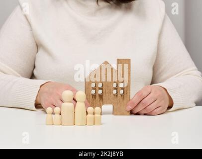 Holzhaus und Figuren einer Familie. Immobilienversicherungskonzept, glückliche Familie Stockfoto