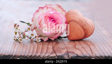 Zarte Rosenblume mit Holzherz Stockfoto