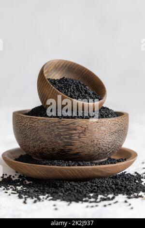 Indisches Gewürz Schwarze Kreuzkümmel (Nigella sativa oder Kalonji) Samen in Holzschüsseln auf weißem Tisch Nahaufnahme Stockfoto