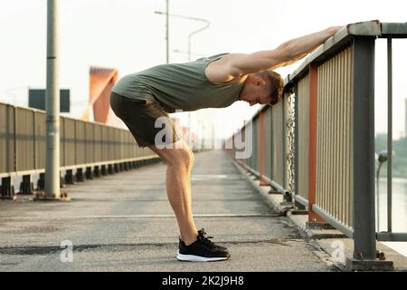 Junger, sportlicher Mann, der sich vor seinem Straßenkraining aufwärmt Stockfoto