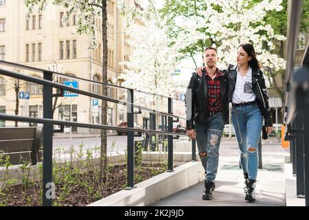 Ein wunderschönes Paar, das während seines Dates Lederjacken trägt und auf einer Straße spaziert. Stockfoto