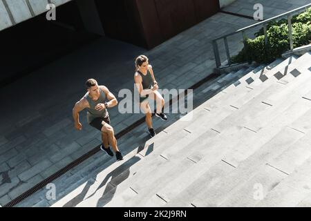 Sportliches Paar beim Training, Treppenlauf im Freien Stockfoto