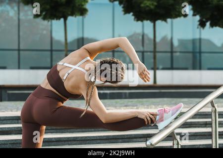 Die sportliche Frau dehnt sich während des Fitnesstrainings im Freien Stockfoto
