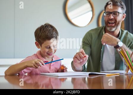 Papa weiß, wie man aus dem Lernen eine unterhaltsame Erfahrung macht. Aufnahme eines Vaters, der seinem kleinen Sohn bei seinen Hausaufgaben hilft. Stockfoto