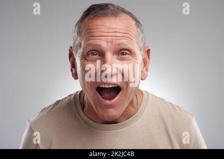 Ich kann das kaum glauben. Aufnahme eines hübschen reifen Mannes, der allein vor grauem Hintergrund im Studio steht und überrascht aussieht. Stockfoto