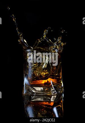 Splash von Whiskey in eckigen Glas Stockfoto