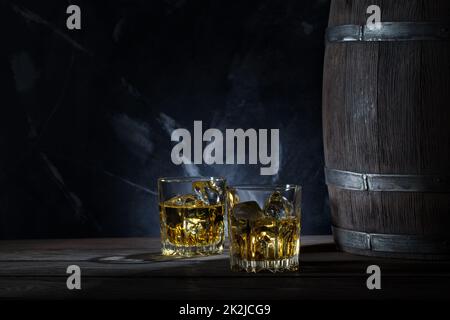 Zwei Gläser Whisky mit Eis und Holzfass Stockfoto