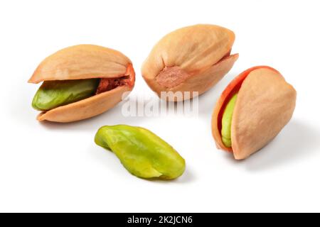 Türkischen Roten geröstete Pistazien in der Schale, einige der grünen Nüsse sichtbar, auf weißem Hintergrund. Stockfoto