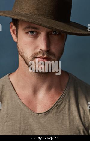 Hüte sind ein tolles Accessoire, um Ihren Stil zu verbessern. Studioporträt eines hübschen jungen Mannes, der einen Hut vor einem dunklen Hintergrund trägt. Stockfoto