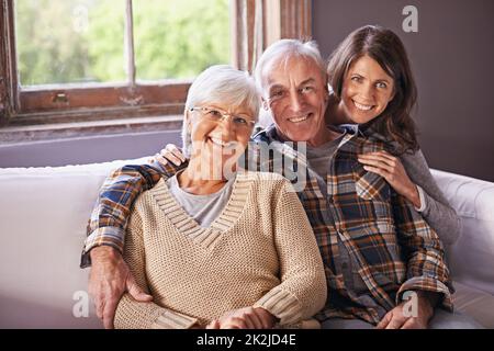 Meine Mutter und mein Vater meinen mir die Welt. Ein beschnittenes Porträt eines glücklichen älteren Ehepaares und ihrer erwachsenen Tochter zu Hause. Stockfoto