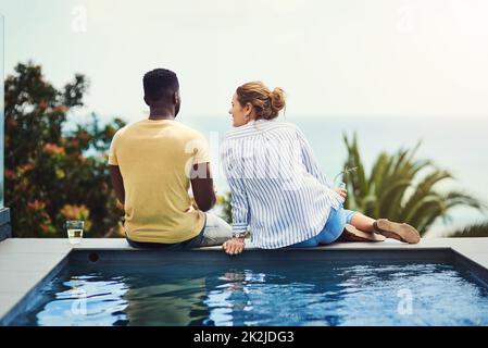 Kamen uns am Tag näher. Rückansicht eines jungen Paares, das zusammen Getränke genießt und sich im Urlaub im Freien entspannt. Stockfoto