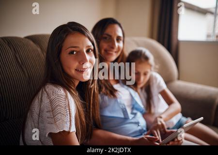 Ich hatte viel Spaß mit dem Internet. Beschnittenes Porträt einer attraktiven Mutter, die sich mit ihren beiden Töchtern zu Hause Filme auf einem Tablet ansieht. Stockfoto