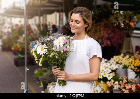 Frau Floristin mit einem Blumenstrauß in ihrem kleinen Blumenladen Stockfoto