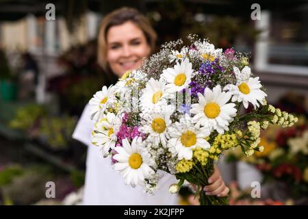 Frau Floristin mit einem Blumenstrauß in ihrem kleinen Blumenladen Stockfoto