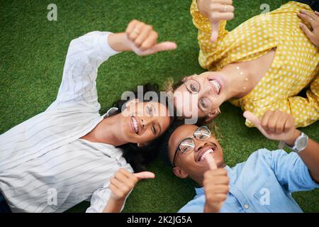 Umweltschutz ist das Geschäft aller. Porträt einer Gruppe junger Geschäftsleute, die in einem modernen Büro Daumen zeigen. Stockfoto