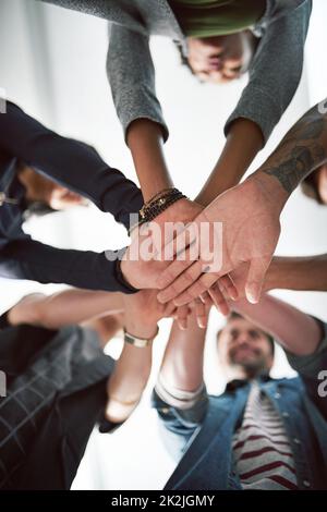 Viele Hände machen leichte Arbeit. Eine kurze Aufnahme einer Gruppe von Menschen, die ihre Hände übereinander stapeln. Stockfoto