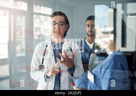 Die Klasse befindet sich in der Sitzung. Schoss eine Gruppe von Ärzten, die Formeln im Büro bei der Arbeit diskutierten. Stockfoto