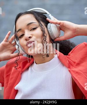 Aufmuntern und gute Musik hören. Aufnahme einer jungen Frau, die Kopfhörer trägt, während sie draußen steht. Stockfoto