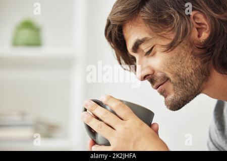 Eine Tasse am Tag hält den Arzt fern. Schuss eines jungen Mannes, der fröhlich eine Tasse Kaffee trinkt. Stockfoto