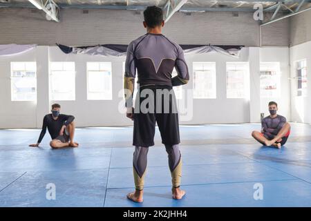 An seine Schüler. Rückansicht eines nicht erkennbaren Jiu-Jitsu-Sensei, der während eines Kurses seine Schüler ansprach. Stockfoto