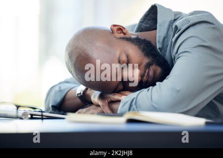 Ich brauche ein fünfminütiges Nickerchen. Aufnahme eines hübschen jungen Geschäftsmannes, der im Büro auf seinem Schreibtisch schläft. Stockfoto