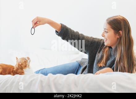 Hes im Begriff, sich dafür zu stürzen. Aufnahme einer jungen Frau, die zu Hause mit ihrer Katze spielt. Stockfoto