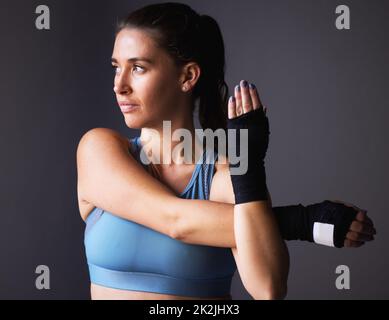 Es ist alles im Kopf. Aufnahme einer jungen Frau, die ihre Arme vor einem grauen Hintergrund streckt. Stockfoto