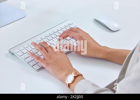 Die letzten ihrer Berichte zusammenzustellen. Nahaufnahme einer unkenntlichen Geschäftsfrau, die in einem Büro an einem Computer arbeitet. Stockfoto