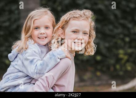 Alle an Bord der Schwester Express. Aufnahme von zwei entzückenden kleinen Mädchen, die Spaß in einem Garten haben. Stockfoto