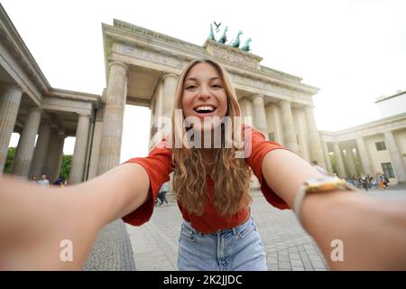 Reisen Sie in Berlin. Fröhliche Touristenfrau macht Selfie-Fotos mit Smartphone-Kamera vor dem Brandenburger Tor, Berlin, Deutschland. Selbstporträt von beau Stockfoto