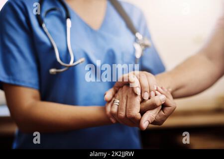 Sie müssen sich Ihren Herausforderungen nicht allein stellen. Ausgeschnittene Aufnahme einer nicht erkennbaren Krankenschwester, die die Hände einer älteren Frau bequem in der Hand hält. Stockfoto