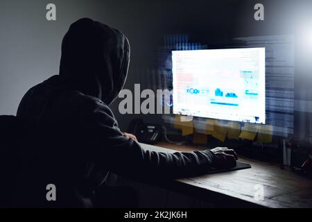 Entwirren des Codes. Rückansicht eines jungen Programmierers, der spät in der Nacht an seinem Computer arbeitet. Stockfoto