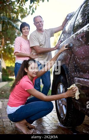 Gemeinsame Bewältigung von Aufgaben. Porträt einer Familie, die draußen ein Auto gemeinsam wäscht. Stockfoto