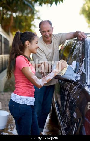 Shes immer bereit zu helfen. Aufnahme eines Vaters und einer Tochter, die draußen ein Auto waschen. Stockfoto