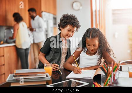 Das ist es, wofür Geschwister sind, um zu helfen. Aufnahme eines Jungen, der seiner Schwester bei ihren Hausaufgaben hilft. Stockfoto