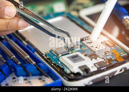 Techniker, der die Leiterplatteninnenseite mit einem Lötkolben repariert. Integrierter Schaltkreis. Das Konzept von Daten, Hardware, Techniker und Technologie. Stockfoto